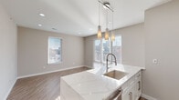 This contemporary apartment showcases a thoughtful design within its 870 square feet of living space. The open floor plan creates a seamless flow between rooms, enhanced by consistent light-toned wood flooring throughout. Large windows in both bedrooms and the living area flood the space with natural light, creating a bright and airy atmosphere.

The kitchen is a highlight, featuring sleek white cabinetry, stainless steel appliances, and a spacious island with pendant lighting. The countertops appear to be quartz or a similar high-end material, adding a touch of luxury. The primary bedroom, at 220 square feet, offers ample space and includes a walk-in closet.

Both bathrooms are well-appointed with modern fixtures, including glass-enclosed showers, white vanities with stone countertops, and large mirrors. The overall color palette is neutral, with soft beige walls complementing the white trim and doors.

The apartment's layout includes two hallways, ensuring privacy between the bedrooms and common areas. The closet space appears generous, with at least one walk-in closet visible. Recessed lighting throughout adds to the modern aesthetic while providing even illumination.

This apartment combines functionality with style, offering a comfortable and contemporary living space ideal for those seeking a turnkey home with upscale finishes.