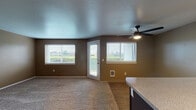 This single-floor unit located on NE Halsey Street in Fairview, Oregon, offers a thoughtfully designed layout with a cohesive warm-toned color palette throughout. The open living and dining area is finished with plush carpet and features multiple windows with horizontal blinds, a glass exterior door providing direct outdoor access, and a ceiling fan with integrated lighting. Views of the surrounding greenery are visible through the windows, adding a pleasant natural element to the space.

The kitchen is well-appointed with dark espresso cabinetry, light-toned granite-style countertops, a peninsula with a built-in sink, and black appliances including a range, oven, refrigerator, and range hood. Track lighting and wood-style flooring complete the functional and attractive kitchen space.

The bedroom offers generous proportions with soft carpeting, natural light from a window, and a mirrored sliding-door closet with built-in shelving. The full bathroom includes wood-style flooring, a dark vanity with a light countertop, a mirror with overhead lighting, and a tub-shower combination. An in-unit laundry area is also present, adding everyday convenience to this well-organized residence.