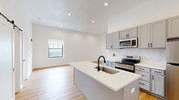 Located on the 11th floor at 933 McGee St in Kansas City, MO, this thoughtfully designed 3-bedroom, 3-bathroom residence offers a clean, contemporary aesthetic throughout. Warm hardwood-style flooring flows seamlessly across the entire single-level floor plan, complemented by crisp white walls and tall ceilings that amplify the sense of openness in every room.

The kitchen and living area form the heart of the home, where a large central island with a white quartz countertop and black matte faucet anchors the space. Gray shaker-style cabinetry, a classic subway tile backsplash, and stainless steel appliances complete the modern kitchen. An in-unit stacked washer and dryer is conveniently tucked in the hallway nearby.

Each of the three bedrooms is generously sized with tall ceilings and large windows that frame impressive city views. Individual wall-mounted climate control units ensure personalized comfort in each room. The spacious primary bedroom features its own en-suite bathroom with a dual-sink marble-top vanity, LED-backlit mirror, and an adjoining walk-in closet with wire shelving. Additional bathrooms maintain the same polished, modern finishes found throughout the unit. The overall ambiance is bright, airy, and move-in ready.