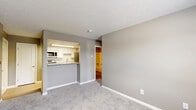 Located at 9115 Knights Bridge Blvd in Indianapolis, IN, this one-bedroom, one-bathroom unit offers a well-designed, single-floor layout that maximizes functionality. Neutral taupe and gray tones throughout create a cohesive, modern aesthetic, complemented by textured ceilings and clean white trim.

The kitchen is a standout feature, equipped with stainless steel appliances including a refrigerator, electric range, and over-the-range microwave. White cabinetry with a subway tile backsplash pairs with granite-style countertops, and light wood-look flooring adds warmth. A pass-through counter connects the kitchen to the main living area, enhancing the open feel of the space.

The carpeted living area is bright and open, with natural light filtering in through a window. The bedroom continues the carpet flooring and features a window with blinds that overlooks greenery, providing a pleasant outdoor view. Two closets offer generous storage, with wire shelving for organization.

The bathroom includes a full tub-shower combination with white tile surround, complemented by wood-look flooring and a granite-topped vanity. A utility room rounds out the layout, adding practical convenience. Overall, this unit delivers a clean, functional living environment with thoughtful finishes throughout.
