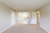 This single-floor residence offers a practical and comfortable layout with a clean, neutral aesthetic carried throughout. The kitchen is well-equipped, featuring white cabinetry extending to the ceiling for ample storage, granite-look countertops, a gas range, a refrigerator, a dishwasher, and a sink beneath a window that brings in natural light. Light-toned ceramic tile flooring runs throughout the kitchen, providing a durable and easy-to-maintain surface. The open living area transitions seamlessly from the kitchen, with soft carpeting underfoot and a bright, airy feel. Multiple bedrooms are accessed via a carpeted hallway, each room finished with neutral-toned walls, plush carpet, and natural light from windows with views of surrounding greenery. Several bedrooms include built-in closets, offering convenient storage. A hallway bathroom features tile wall surrounds and is centrally accessible to the bedrooms. Throughout the residence, white trim and baseboards provide clean contrast against the soft gray and beige wall tones, contributing to a cohesive and move-in-ready appearance. The thoughtful floor plan and consistent finishes make this a functional and welcoming space.