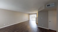 Located at 2101 E Trant Rd in Kingsville, Texas, this single-floor unit offers a practical and well-appointed layout designed for comfortable everyday living. The spacious living and dining area is finished with rich, dark hardwood-style flooring that extends throughout the main spaces, creating a cohesive and polished look. Large sliding glass doors with vertical blinds flood the living area with natural light and provide access to an outdoor balcony, offering pleasant exterior views. A second window near the entryway further brightens the space. The kitchen features granite-style countertops, white cabinetry with wood-tone trim, a stainless steel sink, a dishwasher, and a full-size refrigerator, providing ample functionality for daily use. The bedroom is generously sized, finished with soft carpeting and equipped with a ceiling fan for year-round comfort. The full bathroom includes a wood-framed vanity mirror, granite-style countertop with under-sink storage, and a full tub and shower combination with clean white tile surround. Throughout the unit, neutral warm-gray walls provide a versatile backdrop, and consistent trim details tie each space together cohesively. This single-level layout offers straightforward, accessible living in a residential Kingsville location.