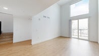 Located in Van Nuys, Los Angeles, this two-story residence offers a clean, modern aesthetic throughout its well-distributed layout. The main floor comprises the generous living area, which immediately impresses with its soaring vaulted ceilings and an abundance of natural light streaming through large floor-to-ceiling windows and a sliding glass door that opens to a private balcony overlooking the surrounding neighborhood. Light wood laminate flooring and crisp white walls create a bright, airy atmosphere throughout.

The two bedrooms are thoughtfully sized, with the primary bedroom offering ample space, large windows with open city views, and a dedicated closet. The second bedroom also benefits from natural light through its own window. The full bathroom is well-appointed, featuring a tub-shower combination with white subway tile surround, a stylish vanity with light blue cabinetry, white stone countertops, a deep basin sink, and a large frameless mirror with matte black accents.

A staircase connects the main floor to the upper level, which provides additional flexible living space. The consistent use of light wood flooring, neutral tones, and modern finishes throughout lends the home a cohesive, contemporary character suited to a variety of lifestyles.