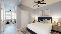Located in Savannah, GA, this single-floor residence offers a thoughtfully designed layout that blends contemporary style with everyday functionality. Light gray walls and light-toned hardwood-style flooring run throughout the space, creating a cohesive and airy atmosphere.

The open-concept living and kitchen area serves as the heart of the home. The kitchen is outfitted with white shaker-style cabinetry, dark countertops, stainless steel appliances including a full-size refrigerator, microwave, and range, and a single-basin sink positioned beneath a window that draws in natural light. A decorative gallery wall adds a curated touch to the kitchen nook. The adjacent living area accommodates a comfortable seating arrangement alongside a media console, and large windows fitted with blinds provide ample natural light and views of the surrounding building exterior.

A separate living space offers additional room for relaxation, featuring ceiling fans, track lighting, and generous window placement. The bedroom is well-proportioned, with a ceiling fan, a private door, and a window that brings in natural light. Framed artwork adorns the walls, contributing to the space's polished, modern aesthetic.

Throughout the residence, clean architectural lines, recessed lighting, and consistent flooring tie each area together into a unified, move-in-ready living environment.