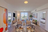 This contemporary 820 square foot apartment in Miami offers a harmonious blend of style and functionality. The open-concept layout maximizes the use of space, creating a seamless flow between the living areas. The kitchen boasts modern appliances, light wood cabinetry, and a convenient dining area with a round glass table.

The living room is bathed in natural light from large windows that offer stunning city views. It's furnished with a comfortable sofa, accent chairs, and tasteful decor, including eye-catching artwork that adds pops of color to the neutral palette.

Both bedrooms are well-appointed, with the primary bedroom measuring 150 square feet. They feature plush bedding, ample storage, and continue the apartment's modern aesthetic with carefully chosen artwork and furnishings.

The two bathrooms are sleek and efficient, with one showcasing a spacious vanity and large mirror. Throughout the apartment, the flooring alternates between warm hardwood and neutral tiles, adding texture and definition to each space.

The apartment's design incorporates clever storage solutions and a thoughtful selection of furniture that complements the compact yet open feel of the space. Artistic elements, from abstract prints to geometric patterns, are consistently used to add visual interest and personality to each room.

With its prime location in Miami (zip code 33128) and its blend of comfort and style, this apartment offers an ideal urban living experience in a space that feels much larger than its 820 square feet would suggest.