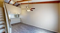 Located in Tempe, Arizona, this two-story, 2-bedroom, 3-bathroom home offers a thoughtfully laid-out floor plan across two levels. The main floor sets an impressive tone with a spacious open-concept living and dining area showcasing soaring vaulted ceilings adorned with striking exposed wood beams — a standout architectural detail that adds warmth and character. Ceiling fans provide comfort, while large windows invite abundant natural light throughout. The kitchen features a peninsula with a white countertop, gray cabinetry, and a pass-through opening to the living area, making it ideal for everyday functionality. Luxury vinyl plank flooring runs throughout, offering a clean, contemporary look. The main level also includes a den, perfect for a home office or flex space, along with convenient closet storage. Upstairs, the two bedrooms are well-proportioned and bright, each with ceiling fans, ample closet space, and natural light from well-placed windows. The primary bedroom offers a comfortable retreat with generous storage. Three full bathrooms — including a walk-in shower — serve the home efficiently. With six closets total and a staircase connecting both levels, this home balances practical storage with an open, airy aesthetic throughout.