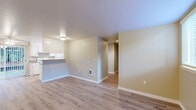This single-floor, 3-bedroom, 2-bathroom residence offers a functional and comfortable layout designed to maximize everyday living. The open-concept living and kitchen area serves as the heart of the home, featuring light-toned hardwood-style flooring, neutral wall tones, and a ceiling fan. A sliding glass door floods the space with natural light and provides access to an outdoor area with lush greenery. The kitchen is laid out in a galley style with white cabinetry on both sides, ample counter space with speckled laminate countertops, a white appliance suite including a range and refrigerator, and an overhead vent hood. A peninsula counter separates the kitchen from the living area, adding definition to the open floor plan. Three carpeted bedrooms offer a comfortable retreat, each featuring neutral tones and natural light from window treatments with blinds — including a generously sized primary bedroom. The two full bathrooms are clean and functional, each equipped with a tub-shower combination, a single vanity with under-cabinet storage, and light wood-style flooring. Additional highlights include three closets for ample storage, a hallway connecting the private quarters, and a dedicated laundry area for added convenience.
