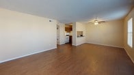 This single-floor unit offers a practical and straightforward layout designed for comfortable everyday living. The open living and dining area is finished with warm hardwood-style flooring and features a ceiling fan overhead, a textured ceiling, and a front entry door flanked by two windows that allow ample natural light to fill the space. The layout flows directly into the kitchen, which is equipped with medium-toned wood cabinetry, a white gas range, a refrigerator, dark countertops, and a tiled backsplash. A breakfast bar counter connects the kitchen to the adjoining area, adding casual dining functionality.

The bedrooms are carpeted and finished with neutral beige walls and textured ceilings. Each room includes at least one window fitted with horizontal blinds, and ceiling fans are present in multiple rooms. Storage is well-addressed, with bedrooms offering either a standard swing-door closet with a built-in shelf and rod or a sliding-door closet of similar configuration.

The bathroom is efficiently arranged, featuring a single-sink vanity with wood cabinetry and a laminate countertop, a wall-mounted mirror with overhead lighting, a toilet, and a tub-shower combination enclosed by white tile surround. Wood-style flooring completes the bathroom. Throughout, the unit maintains a clean, neutral aesthetic suited to a range of furnishing styles.