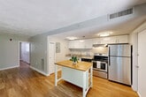 This one-bedroom, one-bathroom unit at 75 Charles Street in Providence, Rhode Island offers a practical and comfortable layout across a single floor. The open-concept kitchen and living area serves as the heart of the unit, featuring warm hardwood-style vinyl flooring that flows throughout the space. The kitchen is well-equipped with stainless steel appliances, including an electric range and refrigerator, complemented by white cabinetry that extends to the ceiling for ample storage. A sliding glass door in the living area fills the space with natural light and provides views of the surrounding greenery, creating an airy, connected feel. The textured ceiling is consistent throughout the unit, adding a classic residential character. The bedroom is a comfortable, well-proportioned room featuring two large closets for generous storage, neutral gray walls, and windows that bring in additional natural light. The bathroom is finished with large-format gray tile flooring, a white vanity, and a full tub and shower surround, maintaining a clean and bright aesthetic. The unit's neutral color palette and consistent flooring create a cohesive, move-in-ready environment suited for everyday living.