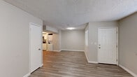 This single-floor residence offers a clean, modern aesthetic highlighted by light-toned luxury vinyl plank flooring that flows consistently throughout every room. The open main living area is bright and welcoming, featuring neutral gray-beige walls, crisp white baseboards, and a textured ceiling. Windows fitted with horizontal blinds allow natural light to filter in while maintaining privacy.

The kitchen is a standout feature, finished with white shaker-style cabinetry, light stone countertops, and a classic white subway tile backsplash. Stainless steel appliances, including a full-size refrigerator and range, provide a polished, functional workspace, while a drop ceiling detail adds architectural character to the space.

The bedrooms are generously sized, each finished with the same consistent flooring and neutral tones. One bedroom features a ceiling fan with lighting, a sliding-door closet, and a window with blinds, while an adjoining bathroom offers a clean, modern finish. An additional bedroom provides a quiet, light-filled retreat with ceiling fan and window access.

The bathroom is well-appointed with a tub-shower combination, a white vanity with stone countertop, a framed mirror, and textured walls for added visual depth. In-unit washer and dryer connections add everyday convenience. Overall, the space presents a clean, updated, and functional living environment.