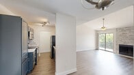 Located at 1221 Chisholm Valley Dr in Round Rock, TX, this 2-bedroom, 2-bathroom home offers a well-designed single-floor layout with a clean, modern aesthetic throughout. Light wood-look flooring flows seamlessly across all living areas, complementing the crisp white walls and bright, open atmosphere.

The combined kitchen and living area serves as the heart of the home. The kitchen features dark navy cabinetry, a white tile backsplash, stainless steel appliances including a microwave, range, and refrigerator, and a peninsula with a light countertop that opens to the living space. The living room impresses with vaulted ceilings, a ceiling fan, a stone-accented fireplace, and a sliding glass door leading to a private balcony with outdoor views.

The primary bedroom is generously sized, offering a ceiling fan, natural light from large windows, and direct access to a closet and bathroom. The second bedroom also features wood-look flooring and ample natural light. Both bathrooms are equipped with full tub-and-shower combinations, finished with large-format neutral tile surrounds and brushed nickel fixtures, providing a clean and functional design. A staircase is also present within the unit.