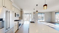 This thoughtfully designed 2-bedroom, 2-bathroom single-floor residence offers a clean, contemporary aesthetic with high-quality finishes throughout. The open-concept kitchen is a standout feature, anchored by an expansive quartz waterfall island with an undermount sink and stylish pendant lighting. Soft-toned shaker cabinetry lines the walls alongside premium stainless steel appliances, including a gas range and built-in refrigerator, with a subway tile backsplash completing the refined look. The kitchen flows seamlessly into the living room, which is bathed in natural light from a generous bank of floor-to-height windows offering views of the surrounding neighborhood. Light hardwood flooring runs throughout the main living areas, adding warmth and continuity. The bedrooms are carpeted for comfort, each offering a tranquil retreat with ceiling fans and ample closet space. A well-organized walk-in closet with multi-tier shelving serves the primary bedroom. The primary bathroom impresses with marble-look tile flooring, a double-sink vanity, a large mirror, and a glass-enclosed walk-in shower with a built-in bench. A clean, well-proportioned hallway connects all rooms efficiently. The overall ambiance is bright, modern, and move-in ready.