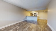 This single-floor unit offers a clean, modern layout designed for comfortable everyday living. The open-concept living and kitchen area serves as the heart of the space, where wood-look luxury vinyl plank flooring flows seamlessly underfoot. The kitchen is well-appointed with white cabinetry, granite-style countertops, a tile backsplash, and a full suite of stainless steel appliances including a refrigerator, electric range, and over-the-range microwave. A peninsula counter provides additional prep space and a natural divider between the kitchen and the generously sized living area. Textured ceilings are present throughout, adding a classic residential character. The bedrooms offer comfortable retreats, each featuring windows with blinds that invite natural light. One bedroom is finished with wood-look plank flooring, while another features plush wall-to-wall carpeting, providing a softer feel underfoot. The bathroom is finished with wood-look vinyl flooring and includes a full tub and shower combination with chrome fixtures and clean white surrounds. Throughout the unit, neutral wall tones and bright white baseboards create a fresh, move-in-ready aesthetic that is both versatile and welcoming.