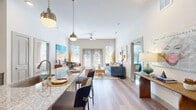 This single-floor residence showcases a thoughtfully designed open-concept layout that seamlessly connects the kitchen, dining, and living areas. Light wood flooring flows consistently throughout, lending warmth and visual continuity to the space. The kitchen is equipped with sleek grey cabinetry, granite countertops, stainless steel appliances, a subway tile backsplash, and pendant lighting above a breakfast bar with seating — an ideal setup for both cooking and casual dining.

The living area is bright and inviting, benefiting from tall ceilings and large French doors that welcome abundant natural light and provide outdoor views. A ceiling fan adds a practical touch to the airy atmosphere.

Multiple bedrooms offer comfortable retreats, each featuring light wood flooring, well-sized windows with outdoor views, and generous closet storage, including a walk-in closet with wire shelving systems. The bathroom is finished with granite-topped dark cabinetry, built-in wall niches, and a glass-enclosed shower, combining functionality with refined detailing. Overall, the residence presents a clean, contemporary aesthetic with a bright, welcoming ambiance throughout.