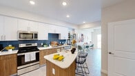 Located at 2500 SW 22nd Terrace in Fort Lauderdale, FL, this well-appointed one-bedroom, one-bathroom residence offers a thoughtfully designed layout with modern finishes throughout. The open-concept living area is filled with natural light from large windows that frame scenic outdoor views, creating an airy and inviting atmosphere. Light-toned tile flooring runs throughout the space, complementing the neutral color palette on the walls. The living room offers generous space for both lounging and a dedicated workspace, with a private balcony accessible through a sliding glass door. The kitchen is a standout feature, showcasing a bold navy tile backsplash, two-tone cabinetry combining white upper cabinets with warm wood lower cabinets, quartz countertops, stainless steel appliances, and a curved peninsula with bar seating — ideal for casual dining and entertaining. The bedroom is a serene retreat with a tray ceiling, ceiling fan, and a cozy, well-proportioned layout. The bathroom is clean and modern, featuring large-format tile flooring, a glass-enclosed shower, and a sleek vanity with ample storage. An in-unit washer and dryer add everyday convenience to this polished Fort Lauderdale residence.
