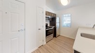 This single-floor unit offers a well-organized layout that balances comfort and functionality. The open living and dining area is finished with light wood-look flooring and features a ceiling fan with integrated lighting, a pendant light over the kitchen counter, and a window that allows natural light to fill the space with warmth throughout the day.

The kitchen is efficiently designed with dark wood cabinetry, light countertops, and a full suite of stainless steel appliances, including a gas range, over-the-range microwave, and refrigerator. Light wood-look flooring continues through the kitchen, creating a cohesive transition from the living area. A closet door near the kitchen entry provides convenient additional storage.

The bedroom is carpeted in a warm, neutral tone and features a window with blinds for natural light and privacy. The room offers a clean, versatile space with crisp white walls and classic white baseboards throughout.

The bathroom is accessed through a paneled white door and features wood-look flooring that matches the rest of the unit. It includes a vanity with dark wood cabinetry, a light countertop, a toilet, and a full bathtub and shower combination. The space is clean and functional with a straightforward, practical layout.

Overall, the unit presents a neutral, move-in-ready aesthetic with consistent finishes and a bright, airy atmosphere.