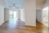 This thoughtfully designed 1-bedroom, 1-bathroom residence offers a well-appointed single-floor layout that maximizes both function and style. The open-concept living area is bright and airy, featuring warm wood-look flooring, crisp white walls, and a ceiling fan. Floor-to-ceiling glass doors invite abundant natural light and provide views of greenery outside, enhancing the sense of openness.

The modern kitchen is a standout feature, equipped with a full suite of stainless steel appliances including a gas range, microwave, dishwasher, and side-by-side refrigerator. Sleek white cabinetry, a subway tile backsplash, and a stone-topped center island with built-in shelving provide ample storage and prep space. Exposed concrete architectural accents add an industrial character that complements the contemporary design.

The bedroom is a comfortable retreat, featuring hardwood-style flooring, large windows with natural light, and exposed concrete beam detailing. A spacious walk-in closet with multi-level shelving and hanging rods offers generous storage.

The bathroom is finished in a clean, modern palette with large-format tile flooring, a marble-tiled walk-in shower, a white vanity with quartz countertop, an oversized mirror, and matte black fixtures throughout.