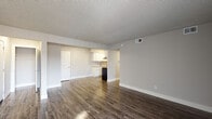 This single-floor unit offers a practical and comfortable layout across two bedrooms and two bathrooms. The open living area is finished with durable wood-style flooring that extends through the main living spaces, complemented by neutral gray-toned walls and a textured ceiling throughout. The space flows naturally toward the kitchen, which features a galley-style configuration equipped with white shaker cabinetry, light granite-style countertops, a stainless steel sink, and black and stainless appliances including a refrigerator and electric range with overhead ventilation.

Both bedrooms are carpeted and finished in neutral tones, each with a window that provides natural light and outdoor views of the surrounding area. The layout, as seen in the floor plan, accommodates clear separation between the living and sleeping areas.

The two bathrooms include a full bath with a tiled tub-and-shower combination and brushed nickel fixtures, and a second bath with a shower-tub unit and wood-style flooring. White trim and clean finishes carry throughout, giving the unit a consistent, well-maintained appearance overall.
