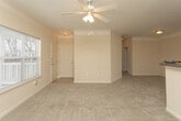 Located at 2100 Education Way in Oakwood, Georgia, this single-floor unit offers a well-organized and functional layout designed for comfortable everyday living. The open living area is a welcoming centerpiece, featuring vaulted ceilings, a ceiling fan, and large windows that invite abundant natural light and outdoor views. Neutral-toned carpet flows throughout, creating a cohesive and warm atmosphere.

The kitchen is positioned adjacent to the living area and is outfitted with warm oak cabinetry, dark granite-style countertops, a tile floor, and a full suite of white appliances including a range, refrigerator, dishwasher, and built-in microwave. A pass-through counter connects the kitchen to the living space, enhancing the open feel.

The bedrooms are generously sized, each carpeted and filled with natural light from well-placed windows. Closet space is provided in each room, with at least one bedroom featuring a walk-in closet. The bathrooms are practically appointed with white vanities, dark countertops, large mirrors, and tub/shower combinations with tiled surrounds. One bathroom includes a high window above the tub, adding a touch of natural light. Throughout the unit, neutral beige walls and clean finishes contribute to a bright, move-in-ready environment.