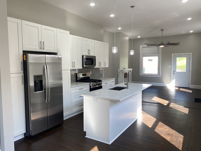 The kitchen features solid wood white cabinets, stainless steel appliances, and quartz countertops - 308 Center St