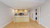 Located in the heart of Washington, DC, this modern 2-bedroom, 2-bathroom residence at 1224 M St NW offers a thoughtfully designed open-concept layout with clean contemporary finishes throughout. Light hardwood flooring runs seamlessly across the entire living area, complementing the bright, neutral palette.

The kitchen is a standout centerpiece, featuring flat-front light wood cabinetry extending to the ceiling, a striking marble-veined quartz waterfall island with an undermount sink, Bosch stainless steel appliances including a gas range, wall oven, and built-in microwave, and a sleek tile backsplash. A stacked in-unit washer and dryer is conveniently integrated nearby.

The open living area benefits from floor-to-ceiling windows that invite abundant natural light and offer views of the surrounding streetscape. Both bedrooms are finished with the same light hardwood flooring and recessed lighting, providing a calm and versatile space.

The two bathrooms are elegantly appointed with large-format marble-look tile flooring, floating wood vanities with white countertops, and frameless glass walk-in showers with full-height tile surrounds. The overall ambiance is polished and minimal, reflecting a modern urban aesthetic ideal for the vibrant Logan Circle neighborhood.