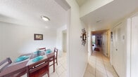 This single-floor residence offers a practical and comfortable layout across two bedrooms and two bathrooms. Light-toned ceramic tile flooring runs throughout the unit, contributing to a bright, cohesive aesthetic. The living room serves as a central gathering space, featuring a large sliding glass door that opens to a private balcony overlooking lush greenery, allowing natural light to fill the room. A textured ceiling is consistent throughout the unit.

The kitchen is efficiently designed with white cabinetry, light countertops, and a pass-through window connecting directly to the living area, enhancing the open feel between spaces. Adjacent to the kitchen, the dedicated dining room accommodates a full dining set comfortably.

A central hallway connects the main living areas to the two bedrooms and bathrooms. The primary bedroom is generously proportioned, featuring tile flooring, a ventilation vent, and access to a full bathroom equipped with a shower-tub combination and white vanity. The second bedroom receives natural light from a large window with outdoor views, making it a versatile space. Both bathrooms maintain a clean, functional design with white fixtures and tile flooring.