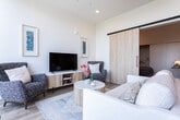 Located at 202 W Broadway in the heart of Salt Lake City, this modern one-bedroom, one-bathroom residence offers a thoughtfully designed single-floor layout with contemporary finishes throughout. Light wood flooring flows seamlessly across the entire space, complementing the clean, minimalist aesthetic.

The open-concept living and kitchen area serves as the centerpiece of the home. The living room is bathed in abundant natural light through dramatic floor-to-ceiling windows and sliding glass doors that open to a balcony, offering sweeping views of the Salt Lake City skyline. The galley-style kitchen features flat-front wood cabinetry, a matching tile backsplash, white countertops, and stainless steel appliances, including a range and built-in microwave.

The bedroom is a quiet retreat with tall ceilings, recessed lighting, and a spacious sliding-door closet with built-in shelving. A tall, narrow window in the entryway corridor further enhances the sense of light and openness while framing additional city views.

The bathroom is sleekly appointed with a floating wood vanity, large mirror, and a frameless glass-enclosed shower, maintaining the home's cohesive modern design. Throughout the space, the bright white walls, warm wood tones, and abundant natural light create a clean, airy ambiance ideal for urban living.