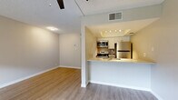 Located at 1045 S San Jose in Mesa, Arizona, this single-floor residence offers a well-designed layout with modern finishes throughout. The open-concept living and kitchen area is a central highlight, featuring a peninsula counter that connects the two spaces seamlessly. The kitchen is equipped with stainless steel appliances — including a refrigerator, range, and microwave — complemented by white upper cabinetry, gray lower cabinetry, and clean white countertops. A ceiling fan overhead and warm wood-look flooring extend into the living area, creating a cohesive and inviting atmosphere.

The living area benefits from a large window that frames views of the green communal grounds outside, filling the space with natural light. Additional rooms feature the same durable wood-look flooring and neutral wall tones, providing a versatile backdrop for any décor style.

The bathroom is thoughtfully appointed with a full tub-shower combination and a separate vanity area featuring gray cabinetry, a white countertop, and a well-lit mirror with louvered closet access nearby. A dedicated laundry area houses a stacked washer and dryer unit alongside closet storage, adding everyday convenience. Textured ceilings are consistent throughout, and the overall design reflects a clean, updated aesthetic well-suited for comfortable living in the Mesa area.