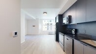 Located in Portland's North Jessup Street neighborhood, this modern residence offers 2 bedrooms and 3 bathrooms across a single, efficiently designed floor. The open-concept living and kitchen area is anchored by a sleek, contemporary kitchen featuring floor-to-ceiling dark cabinetry, black granite countertops, a full suite of Whirlpool stainless steel appliances — including an electric range, built-in microwave, dishwasher, and refrigerator — and a undermount sink. Light hardwood flooring flows throughout, contrasting cleanly against the bright white walls and ceilings. The primary bedroom is a well-proportioned retreat with a large picture window that frames views of the surrounding neighborhood and fills the room with natural light. Both bedrooms include sliding-door closets with built-in shelving and hanging rods. The three bathrooms maintain a consistent modern aesthetic, featuring dark matte hardware and fixtures; one includes a soaking tub/shower combination, while another offers a walk-in shower. A stacked in-unit washer and dryer provides added convenience. The overall design is clean, minimal, and contemporary, making efficient use of every square foot.