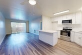 Located at 6401 Warner Ave in Huntington Beach, CA, this 2-bedroom, 1-bathroom residence offers a thoughtfully laid-out single-floor plan. The open-concept kitchen and living room serve as the heart of the home, featuring wood-style plank flooring that extends throughout the main living areas. The kitchen is well-appointed with crisp white shaker cabinetry, light countertops, a central island, and stainless steel appliances including an electric range and over-the-range microwave. A sliding glass door in the living room floods the space with natural light and opens to a private balcony with outdoor views. Both bedrooms are carpeted and feature sliding-door closets and vertical blinds. The primary bedroom offers a comfortable, well-proportioned layout. The full bathroom is finished in a clean, bright palette with a white vanity, tub-shower combination, and wood-style flooring. A hallway connects the private areas of the home, completing the functional floor plan. The overall aesthetic is clean and modern, with a light, airy ambiance throughout.