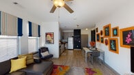 Located at 630 Cotanche St in Greenville, NC, this single-floor unit offers a thoughtfully designed open-concept layout with a contemporary aesthetic. The living area is bright and welcoming, featuring large windows dressed with striped Roman shades and blinds that allow generous natural light to fill the space. A ceiling fan overhead, hardwood-style flooring, and a vibrant area rug add warmth and character, while a gallery wall with bold orange frames serves as a striking focal point alongside the entertainment area.

The kitchen is efficiently laid out with light wood cabinetry, stainless steel appliances including a range, microwave, dishwasher, and refrigerator, complemented by a fun chalkboard accent wall. A dedicated dining area sits adjacent to the kitchen, offering a comfortable space for meals.

The bedrooms are individually styled, each with ceiling fans and ample natural light. One bedroom features a rich purple accent wall and a built-in desk area, while another offers a cozier, earthy atmosphere.

The bathrooms are clean and well-appointed. One features a wide vanity with light wood cabinetry and a separate tub/shower combination, while another offers a standard tub-shower setup. Hardwood-style flooring flows consistently throughout, tying the entire unit together cohesively.