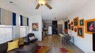 Located at 630 Cotanche St in Greenville, NC, this single-floor unit offers a thoughtfully designed open-concept layout with a contemporary aesthetic. The living area is bright and welcoming, featuring large windows dressed with striped Roman shades and blinds that allow generous natural light to fill the space. A ceiling fan overhead, hardwood-style flooring, and a vibrant area rug add warmth and character, while a gallery wall with bold orange frames serves as a striking focal point alongside the entertainment area.

The kitchen is efficiently laid out with light wood cabinetry, stainless steel appliances including a range, microwave, dishwasher, and refrigerator, complemented by a fun chalkboard accent wall. A dedicated dining area sits adjacent to the kitchen, offering a comfortable space for meals.

The bedrooms are individually styled, each with ceiling fans and ample natural light. One bedroom features a rich purple accent wall and a built-in desk area, while another offers a cozier, earthy atmosphere.

The bathrooms are clean and well-appointed. One features a wide vanity with light wood cabinetry and a separate tub/shower combination, while another offers a standard tub-shower setup. Hardwood-style flooring flows consistently throughout, tying the entire unit together cohesively.