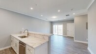 Located at 2421 Bristol Road in Warrington, PA, this thoughtfully designed two-bedroom, one-bathroom residence offers a clean, contemporary aesthetic across a well-appointed single floor. The open-concept kitchen and living area serves as the heart of the home, where crisp white shaker cabinetry, a striking marble-look quartz peninsula with an undermount sink, and a full suite of stainless steel appliances create an inviting and functional space. Crown molding and recessed lighting add refined detail throughout the main living area, which opens to a sliding glass door leading to a private balcony. Light-toned wood-look flooring runs seamlessly through the living spaces, enhancing the bright, airy feel. The generously sized primary bedroom features its own access to an adjacent closet, while the second bedroom benefits from large windows that flood the room with natural light. The hallway area includes a spacious double-door closet and provides easy access to the full bathroom, which is finished with elegant marble-look tile on both the floors and tub surround, complemented by brushed gold fixtures. Neutral gray walls and white trim throughout give the space a cohesive, modern character.