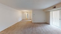 This single-floor residential unit offers a practical and comfortable layout with a variety of well-defined living spaces. The kitchen is equipped with warm oak cabinetry, white appliances including a gas range and over-the-range microwave, a stainless steel sink, and light countertops. A window provides natural light and ventilation, making the space functional and efficient.

The open living and dining area is generously proportioned, featuring neutral carpet flooring, a textured ceiling, and an elegant chandelier that anchors the dining section. The layout flows seamlessly toward the entryway, creating an inviting and cohesive common area.

The bedrooms are carpeted and bright, each featuring windows with blinds that allow natural light while maintaining privacy. The primary bedroom includes dual closets with built-in shelving, offering ample storage. Additional bedrooms are similarly well-sized with their own windows and easy access to the hallway.

The bathroom is finished with white tile wainscoting accented by a distinctive burgundy tile border, complemented by vinyl tile flooring featuring a matching accent pattern. It includes a vanity with an oak cabinet base, a large mirror with overhead lighting, a toilet, and a tub with a shower curtain rod.

Overall, the unit presents a clean, functional, and well-maintained interior suited for comfortable everyday living.