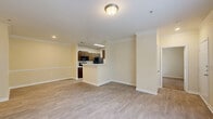Located at 1750 Coloums Drive in Gainesville, GA, this well-appointed two-bedroom, two-bathroom residence offers a comfortable and functional single-floor layout. The open-concept living and kitchen area forms the heart of the home, featuring warm light yellow walls, crown molding, and durable light-toned hardwood-style flooring that flows throughout the main living spaces. The kitchen is efficiently designed in a galley style, equipped with rich dark brown cabinetry, light quartz countertops, black appliances including a range, refrigerator, and dishwasher, and ample upper and lower cabinet storage. A breakfast bar peninsula connects the kitchen seamlessly to the living room. Both bedrooms are carpeted and offer a quiet, cozy atmosphere. The primary bedroom is generously sized and includes a walk-in closet with wire shelving for organized storage. The second bedroom benefits from a window with views of lush greenery outdoors. Each bathroom features dark wood vanity cabinetry, light countertops, a mirror, and hardwood-style flooring, with one bath including a shower-tub combination. A dedicated in-unit laundry area accommodates a full-size washer and dryer. Crown molding and consistent neutral tones create a cohesive, clean aesthetic throughout the entire residence.