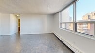 Located on the sixth floor at 55 Park St E in Mississauga, this one-bedroom, one-bathroom unit offers a well-organized layout with a practical mix of living spaces. The kitchen is fitted with dark cabinetry, stainless steel appliances including a French door refrigerator, stove, and microwave, and features grey tile flooring. A pass-through window connects the kitchen to the living area, enhancing the open feel between the two spaces. The living room is generously proportioned, featuring herringbone-patterned parquet flooring, baseboard heating, and large windows that allow for natural light and provide views of the surrounding Mississauga neighbourhood. A sliding glass door leads to an outdoor balcony area with open views. The bedroom offers a comfortable footprint and is equipped with full-wall mirrored sliding closet doors that add depth to the room. The bathroom is finished with warm beige horizontal tile surrounding a full soaker tub and shower combo with chrome fixtures. Throughout the unit, textured ceilings and white walls maintain a clean, neutral aesthetic. The space provides a functional and comfortable living environment in a well-established area of Mississauga.