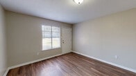 This single-story, one-bedroom, one-bathroom unit in Memphis, Tennessee offers a practical and comfortable layout designed to maximize every square foot. Rich, dark wood-look flooring flows consistently throughout the living areas and bedroom, complemented by neutral gray-toned walls and clean white trim that create a bright, cohesive aesthetic.

The living area greets you at entry, where a front-facing window fitted with horizontal blinds allows natural light to fill the space. The open flow connects seamlessly to the bedroom, which also features a window overlooking the surrounding neighborhood and includes a closet for convenient storage.

The kitchen is outfitted with warm wood cabinetry, dark speckled countertops, and a stainless steel single-basin sink, offering functional prep and storage space. A notable feature is the dedicated in-unit laundry area, which houses a stacked washer and dryer unit alongside a double-basin stainless steel sink — a practical and convenient amenity.

The bathroom features a full tub-shower combination with white tile surround, a window for natural ventilation, classic hexagonal tile flooring, and chrome fixtures. Textured ceilings are present throughout, adding a traditional character to the overall interior. This well-maintained unit delivers efficient, move-in-ready living in a straightforward, functional floor plan.