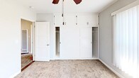 Located at 3120 Hollypark Dr in Inglewood, California, this single-floor unit offers a well-organized layout with a thoughtful blend of hard and soft flooring surfaces. The living area transitions seamlessly between rich dark hardwood-style flooring and plush carpeting, creating distinct zones within an open, light-filled space. Neutral gray walls and clean white baseboards run throughout, lending the interior a modern, cohesive aesthetic.

The kitchen is equipped with stainless steel appliances, including a gas range, over-the-range microwave, and full-size refrigerator, all complemented by dark espresso cabinetry that adds contrast and depth. Hardwood-style flooring continues through the kitchen, providing a durable and easy-to-maintain surface.

The bedrooms are carpeted for comfort and feature ceiling fans with lighting. One bedroom showcases a generous built-in closet system with sliding panel doors and upper storage cabinets, maximizing organizational capacity. Large windows dressed with vertical blinds allow ample natural light while maintaining privacy.

The bathroom is well-appointed with a dark-framed vanity mirror, white sink vanity with granite-style countertop, a soaking tub with shower, and a frosted window for natural light. Dark hardwood-style flooring ties the bathroom's design together with the rest of the unit. Overall, the space presents a clean, updated interior ready for comfortable everyday living.