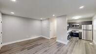 This thoughtfully renovated single-floor unit offers a clean, modern aesthetic throughout, combining functionality with contemporary finishes. The open living and dining area is anchored by durable luxury vinyl plank flooring in a warm gray tone, recessed lighting, and neutral gray walls that create a bright, welcoming atmosphere. A central hallway connects the main living spaces efficiently, with ample wall venting indicating a well-integrated HVAC system.

The kitchen is a standout feature, outfitted with dark gray shaker-style cabinetry, white quartz countertops, a classic subway tile backsplash, and a full suite of stainless steel appliances including a gas range, over-the-range microwave, dishwasher, and refrigerator. A window provides natural light, and the stacked washer and dryer unit is conveniently located just adjacent to the kitchen area.

Two bedrooms are finished with plush carpeting, ceiling fans with integrated lighting, and windows dressed with blinds. One bedroom includes a wall-mounted air conditioning unit for supplemental climate control. Each room also features a closet for storage.

The bathroom is clean and efficient, featuring a white vanity with brushed nickel hardware, an integrated sink, a mirrored medicine cabinet, and a toilet. The unit's overall design prioritizes practicality and modern comfort in a well-maintained layout.