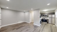 This thoughtfully renovated single-floor unit offers a clean, modern aesthetic throughout, combining functionality with contemporary finishes. The open living and dining area is anchored by durable luxury vinyl plank flooring in a warm gray tone, recessed lighting, and neutral gray walls that create a bright, welcoming atmosphere. A central hallway connects the main living spaces efficiently, with ample wall venting indicating a well-integrated HVAC system.

The kitchen is a standout feature, outfitted with dark gray shaker-style cabinetry, white quartz countertops, a classic subway tile backsplash, and a full suite of stainless steel appliances including a gas range, over-the-range microwave, dishwasher, and refrigerator. A window provides natural light, and the stacked washer and dryer unit is conveniently located just adjacent to the kitchen area.

Two bedrooms are finished with plush carpeting, ceiling fans with integrated lighting, and windows dressed with blinds. One bedroom includes a wall-mounted air conditioning unit for supplemental climate control. Each room also features a closet for storage.

The bathroom is clean and efficient, featuring a white vanity with brushed nickel hardware, an integrated sink, a mirrored medicine cabinet, and a toilet. The unit's overall design prioritizes practicality and modern comfort in a well-maintained layout.