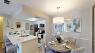 This single-floor residence offers a thoughtfully designed layout that connects living, dining, and kitchen areas in a cohesive, open flow. The kitchen is organized in a galley configuration, featuring white cabinetry, light countertops, wood-look flooring, and a full suite of stainless steel appliances including a refrigerator, electric range, and built-in microwave. A single-basin sink with a modern faucet anchors one side of the kitchen, while an electrical panel is discreetly integrated into the space.

The dining area sits adjacent to the kitchen and is defined by a pendant light fixture overhead and wood-look flooring underfoot. The living room is a comfortable, light-filled space with a fireplace, ceiling fan, sliding glass door that opens to an outdoor view, and large windows dressed with patterned drapes that allow natural light to fill the room.

The bedroom provides a quiet retreat with natural light from a window, a reach-in closet with bifold doors, and wood-look flooring. The bathroom includes a single-sink vanity with white cabinetry, a tub-shower combination, and matching wood-look flooring. Throughout the residence, a neutral color palette and textured ceilings contribute to a consistent, understated aesthetic.