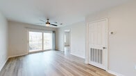 This thoughtfully laid-out 2-bedroom, 2-bathroom residence occupies a single floor and offers a bright, cohesive living environment throughout. Light-toned wood-style flooring runs consistently across all rooms, creating a clean and unified aesthetic. The open living room is a standout space, featuring a ceiling fan, sliding glass doors that lead to a private balcony, and views of the surrounding exterior — allowing abundant natural light to fill the room. A pass-through counter connects the living area to the kitchen, which is equipped with white cabinetry, light countertops, stainless steel appliances including a refrigerator, range, and over-the-range microwave, and track lighting overhead. Both bedrooms are well-proportioned, each featuring a ceiling fan and window with exterior views — one offering a glimpse of a pool area. The primary bedroom is a comfortable size with its own closet. The bathrooms are finished with white cabinetry, a single-sink vanity, and a tub-shower combination with clean white surround. Two closets provide additional storage throughout the unit. A hallway connects the private areas of the home to the main living spaces, completing the functional and efficient floor plan.
