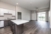 This well-appointed 2-bedroom, 2-bathroom unit in Clear Lake, Iowa, offers a thoughtfully designed layout with modern finishes throughout. The open-concept kitchen serves as a focal point, featuring a large center island with a light quartz countertop, two-tone cabinetry with dark lower cabinets and crisp white uppers, stainless steel appliances, and durable wood-look flooring. The kitchen flows seamlessly into the living area, which benefits from a ceiling fan and a sliding glass door that opens to a private balcony, filling the space with natural light and outdoor views. Both bedrooms are carpeted for comfort, with the primary bedroom offering generous proportions and a walk-in closet equipped with wire shelving. The second bedroom features a large window that frames neighborhood views. Two full bathrooms provide practical functionality — one includes a tub-shower combination with a dark-cabineted vanity, while the other offers a walk-in shower with grab bar. A dedicated in-unit laundry room houses a full-size washer and dryer with additional wire shelving above for storage. Two closets throughout the unit further enhance organizational capacity. Neutral tones and consistent flooring choices throughout create a clean, cohesive aesthetic.