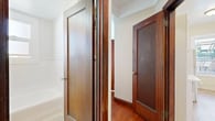This well-appointed 1-bedroom, 1-bathroom residence showcases a thoughtful layout that maximizes every square foot across a single floor. Rich, warm hardwood floors run throughout the main living and bedroom areas, complemented by dark-stained wood trim, door frames, and baseboards that lend the space a classic, timeless character.

The spacious primary bedroom is a standout feature, highlighted by a graceful bay window fitted with blinds that invite an abundance of natural light while offering privacy. Crown molding along the ceiling adds an elegant architectural detail, and a built-in closet with a wood-framed opening provides practical storage.

The hallways connect the rooms efficiently, maintaining a cohesive flow throughout the residence. The bathroom features classic hexagonal mosaic tile flooring and a full bathtub, framed by the same rich wood door surrounds found throughout the space. A window allows natural light to brighten the room.

The kitchen area includes full-size appliances and open shelving, offering functional storage solutions. Tile flooring grounds this area and transitions cleanly from the hardwood found in adjoining spaces.

Overall, the residence presents a blend of vintage architectural charm — evident in its crown molding, rich woodwork, and bay window — with a practical and efficient floor plan suited for comfortable everyday living.