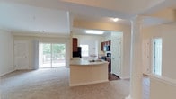 This well-appointed three-bedroom, two-bathroom single-story home offers a thoughtfully designed layout with a comfortable sense of scale throughout. The open-concept living and kitchen area serves as the heart of the home, where a peninsula with a built-in sink and light countertops connects the kitchen to the carpeted living room. Rich dark-wood cabinetry, black appliances, and durable hardwood-style flooring give the kitchen a functional yet polished character. A sliding glass door in the living area provides direct access to an outdoor space and fills the room with natural light. Adjacent to the kitchen, a dining area features built-in corner shelving and a large window overlooking greenery outside.

Each bedroom is carpeted and equipped with a ceiling fan. The primary bedroom benefits from multiple windows and connects to a private en-suite bathroom featuring a double-sink vanity with dark cabinetry, a glass-enclosed shower, and a walk-in closet. The secondary bathroom includes a single-sink vanity and a shower-tub combination. Additional bedrooms offer closet access and natural light. The spacious attached two-car garage provides ample storage and parking with an automatic door opener.