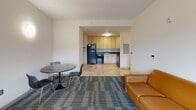 Located at 115 S Quarry St in Ithaca, NY, this 2-bedroom, 2-bathroom unit offers a functional and modern layout across a single floor. The open-concept living area flows seamlessly into a well-appointed kitchen featuring light wood cabinetry, dark granite-style countertops, and black appliances including a refrigerator, oven, and dishwasher. The living space is finished with patterned carpet tile and includes a dining area, making it both practical and comfortable.

Both bedrooms are carpeted and filled with natural light from large windows that frame tranquil wooded views. The primary bedroom is generously sized and includes a built-in desk with upper shelving — ideal for a dedicated study or work area. The second bedroom also features a wide window with scenic tree views, providing a calm retreat.

Each bathroom is finished with warm travertine-style tile flooring and includes a light wood vanity with a dark countertop and a large mirror. The clean, neutral palette throughout creates a cohesive and modern aesthetic.

A hallway and closet complete the layout, adding to the unit's practical storage and circulation. The overall design emphasizes clean lines, natural light, and views of the surrounding landscape, making this a well-rounded and thoughtfully designed space.
