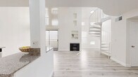 Located at 825 S Hobart Blvd in Los Angeles, this two-story, 2-bedroom, 2-bathroom home offers a clean, modern aesthetic defined by an all-white palette and light wood-style flooring throughout. The main floor is expansive, anchored by an open-concept living room featuring soaring ceilings, a classic fireplace with built-in wall niches, and abundant natural light streaming through vertical-slatted windows. A sculptural white spiral staircase serves as both a functional and architectural centerpiece, leading to the upper level. The well-appointed kitchen features crisp white shaker cabinetry with matte black hardware, granite countertops, stainless steel appliances, and recessed lighting, providing ample storage and prep space. Both bathrooms are finished with granite vanity tops, white cabinetry, and tub-shower combinations with glass sliding doors. The two bedrooms are bright and generously proportioned, with the primary bedroom offering comfortable square footage, recessed lighting, and easy access to additional closet space. Three closets throughout the home provide excellent storage. The upper floor offers a more intimate, private retreat. Clean lines, neutral tones, and thoughtful finishes give this home a move-in-ready appeal in the heart of Los Angeles.