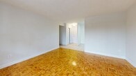 Located at 20 Trudelle Street in Toronto's Scarborough area, this 2-bedroom, 1-bathroom unit offers a functional and well-laid-out floor plan across a single level. The combined living and dining area is a standout feature, showcasing classic parquet wood flooring in a warm honey tone that reflects natural light from a large picture window overlooking the neighbourhood. The space flows seamlessly into a welcoming entry hallway with tile flooring connecting to the rest of the unit. The kitchen is outfitted with white cabinetry, granite-style countertops, a neutral tile backsplash, and tile flooring, providing ample storage and a clean, practical workspace. Both bedrooms feature light hardwood flooring, wide windows with outdoor views of surrounding greenery, and classic cast-iron radiators. The primary bedroom offers a generous footprint with good natural light. The bathroom includes a full soaker tub with white subway tile surround and a vanity with mirror. Three closets throughout the unit provide substantial storage. A private balcony with teal railings extends the living space outdoors, offering open views of the surrounding area. The unit includes a dedicated hallway entry for added privacy.