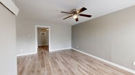 Located at 6705 Fairway Dr in Houston, TX, this single-floor, one-bedroom, one-bathroom unit offers a practical and well-designed layout. Light wood-style flooring runs continuously throughout, creating a cohesive and clean aesthetic across every room.

The open-concept kitchen and living area form the heart of the unit. The kitchen is equipped with stainless steel appliances — including a full-size refrigerator, range, and over-the-range microwave — complemented by gray shaker-style cabinetry and granite-look countertops. A wall-mounted light fixture adds task lighting to the space. The adjacent living area is bright and open, with a ceiling fan overhead and windows that allow natural light to filter in.

The bedroom is a comfortable, well-proportioned room featuring its own ceiling fan with light kit and a window for natural ventilation. A wall-mounted AC unit provides supplemental climate control. The room connects to a dedicated closet with built-in shelving, offering organized storage.

The bathroom features a tiled tub-and-shower combination with a curved curtain rod and a gold-toned finish. Large-format tile lines the walls, while striped tile flooring adds a subtle design detail. A window above the tub provides natural light and ventilation.

Overall, the unit presents a clean, updated interior with neutral tones and functional finishes throughout.