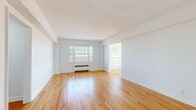 Located at 2680 N Moreland Blvd in Cleveland's Shaker Square neighborhood, this well-maintained single-floor unit offers a clean, light-filled interior defined by warm hardwood flooring and crisp white walls throughout. The spacious living area features wide-plank hardwood floors, a large multi-pane window that draws in generous natural light, and a baseboard heating unit, creating a bright and comfortable gathering space. A connecting hallway with recessed lighting leads seamlessly to the private rooms. The bedrooms are distinguished by classic herringbone-patterned hardwood floors, ceiling fans, and windows that allow ample sunlight to filter in; one bedroom includes a built-in closet with shelving. The kitchen is equipped with stainless steel appliances including an electric range, granite countertops, gray cabinetry, and white tile flooring, offering a functional and modern cooking space. A bathroom with classic fixtures is also present. Throughout the unit, the combination of traditional herringbone and straight-lay hardwood floors, white panel doors with black hardware, and an abundance of natural light from multiple windows creates a cohesive, timeless aesthetic that balances classic character with modern updates.